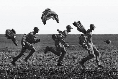 Black-and-white reference photograph of workers crossing a field