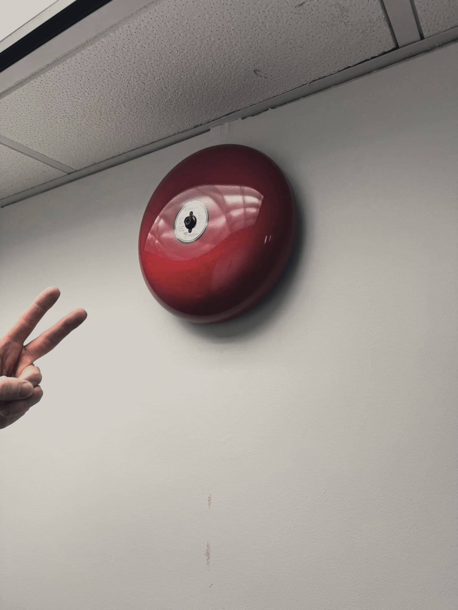 A hand beside a fire alarm bell
